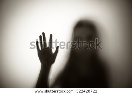 Diffused silhouette of woman through frosted glass