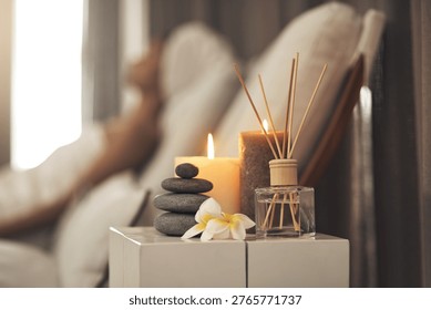 Diffuser, candles or stack of rocks in spa, aromatherapy treatment or soothing atmosphere for relaxation. Peace, burning scent or fragrance setup on table in wellness center, person or zen ambient