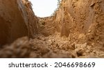 Dig a trench. Earthworks, digging trench. Long earthen trench dug to lay pipe or optical fiber. Construction the sewage and drainage. View from the trench. Clay soil. Part of the image is blurred