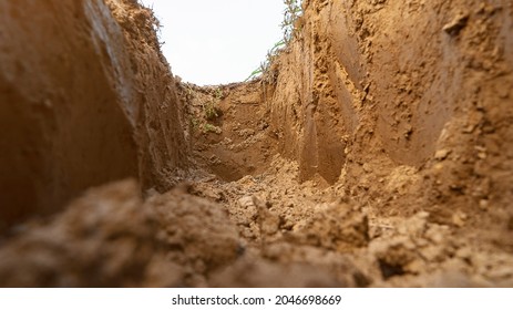 Dig a trench. Earthworks, digging trench. Long earthen trench dug to lay pipe or optical fiber. Construction the sewage and drainage. View from the trench. Clay soil. Part of the image is blurred
