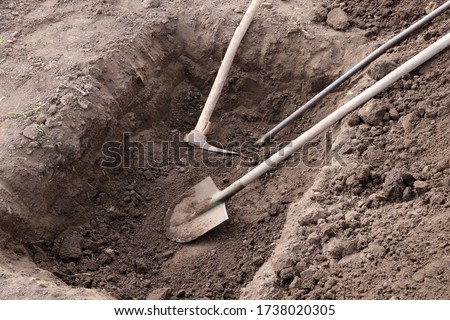 Digging a pit. Pit in the ground. The shovel, pickaxe and crowbar lay in the pit.