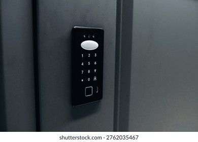 Digital access control keypad with numeric buttons and a fingerprint scanner installed on a gray wall for secure entry into a building or room