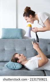 Digital addiction and couple cohabitation problem concept. Woman yelling on megaphone to achieve attention of his boyfriend.