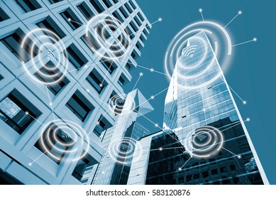 Digital Alarm Icon And Low Angle View Modern Office Buildings In Blue Tone  With Network Connection Concept,  Smart City And Wireless Communication Network, IOT Internet Of Things Conceptual Image