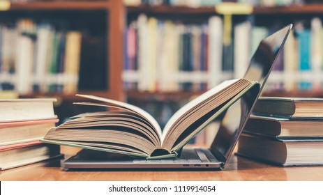 Digital archive, e-learning class and e-book technology in education concept with pc computer notebook open in blur school library, classroom background among old stacks of book, textbook collection