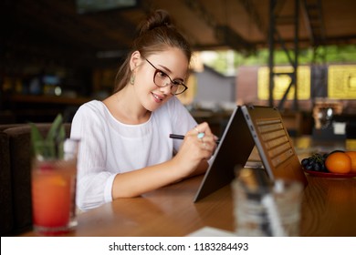 Digital artist drawing sketch with stylus on convertible 2 in 1 laptop display in tent mode. Mixed race multiethnic asian caucasian woman working on project design or writing notes on touchscreen.
