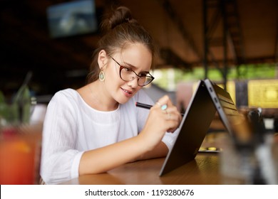 Digital artist drawing sketch with stylus on convertible 2 in 1 laptop display in tent mode. Mixed race multiethnic asian caucasian woman working on project design or writing notes on touchscreen.