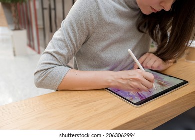 A digital artist draws on a graphic screen tablet, modern technologies for creativity. A young woman artist or designer uses a tablet to draw - Powered by Shutterstock