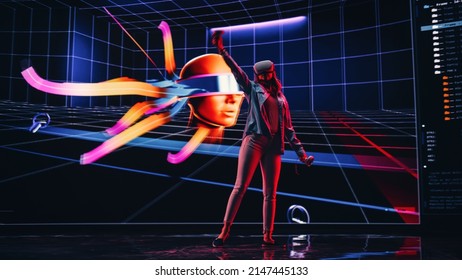 Digital Artist Using VR Software To Create A 3D Piece Of Art: Designing A Stylish Futuristic Portrait In Interactive Environment On A Big Digital Screen. Female Designer Using Headset And Controllers.