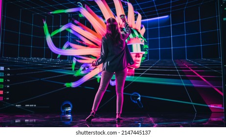 Digital Artist Using VR Software To Create A 3D Piece Of Art: Designing A Stylish Futuristic Portrait In Interactive Environment On A Big Digital Screen. Female Designer Using Headset And Controllers.