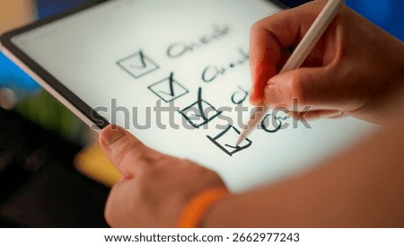 Digital checklist marked tasks completion on tablet screen with stylus. Close-up view of hand ticking checkboxes representing progress, organization and productivity in digital workspace