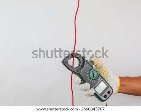 Digital clamp meter held by hand to test current and ampere in electronics. Isolated background 