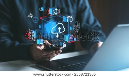 Digital cloud and data security icons over a user holding a smartphone, a laptop in the background, blue and red tones, concept of online storage