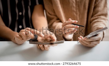 Digital collaboration and mobile technology concept. Two people using smartphones together to share information and communicate online. smartphone, teamwork, communication, connectivity, collaboration