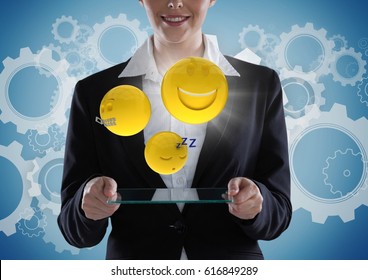 Digital composite of Business woman with glass device and emojis with flare against blue background with gears - Powered by Shutterstock