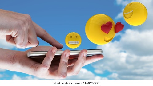 Digital composite of Digitally generated image of emojis flying over hands using smart phone against sky - Powered by Shutterstock