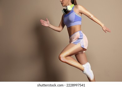 Digital composite of highlighted bones and woman in sportswear with headphones running on beige background - Powered by Shutterstock