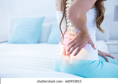 Digital Composite Of Highlighted Spine Of Woman With Back Pain At Home