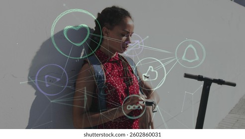 Digital composite image of network of digital icons against african american woman using smartwatch. global networking and technology concept