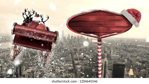 Digital composite of Santa in sleigh with reindeer flying and Christmas sign over city