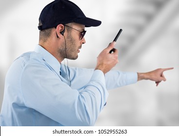 Digital composite of security guard with headphones and speaking with the walkie-talkie. Light blurred background - Powered by Shutterstock