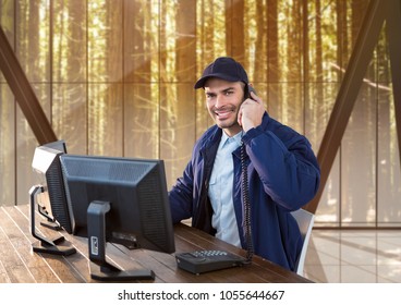 Digital Composite Of Security Guard Technology Phoning And Smiling, Sitting In His Desk. In The Office