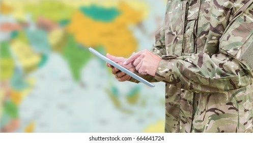 Digital composite of Soldier mid section with tablet against blurry map