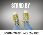 Digital composite of Stand by text and Yellow shoes on feet with grey background