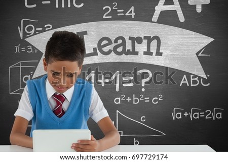 Digital composite of Student boy at table using a tablet against green blackboard with learn text and education and schoo