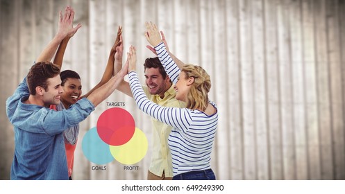 Digital Composite Of Team Highfiving Against Colourful Ven Diagram And Blurry Wood Panel