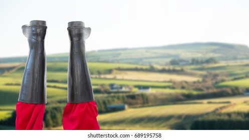 Digital composite of Wellington boots wellies upside down in front of farm landscape nature countryside