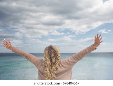 Digital composite of Woman with open arms practicing casual mindfulness in front of sea - Shutterstock ID 698404567