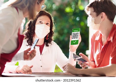 Digital covid-19 vaccination certificate on mobile phone. Coronavirus vaccinated people scan QR code on restaurant entrance. Negative test, completed vaccine and immunity proof for safe travel.