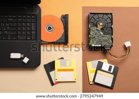Digital data storage evolution: laptop, CD-ROM, hard drive, USB, and floppy disks on a multi-colored background