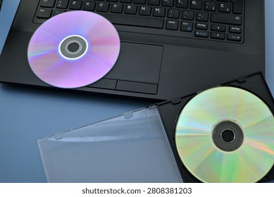 Digital Data Storage: Laptop and CD Against a Blue Background
