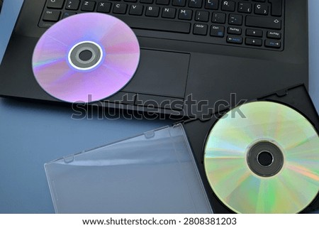Digital Data Storage: Laptop and CD Against a Blue Background
