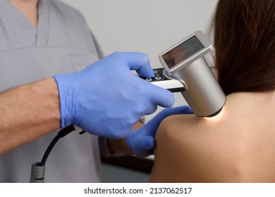 Digital dermatoscopy of moles. A dermatologist-oncologist examines the patient's moles using a dermatoscope. Prevention and early diagnosis of skin melanoma. Dermatological clinic. Close-up shot.