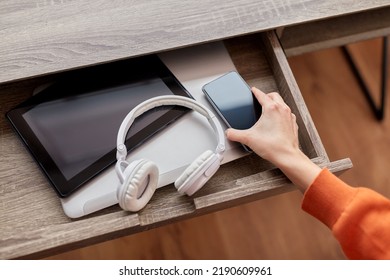 digital detox and technology concept - close up of hand with smartphone and different gadgets in desk drawer at home - Shutterstock ID 2190609961