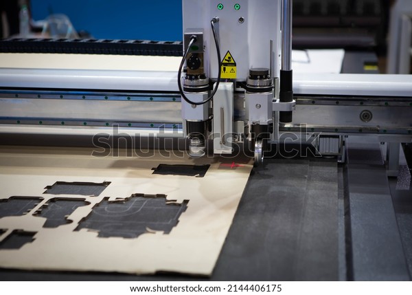 Digital die cutter machine\
cutting corrugated cardboard box for packaging. Industrial\
manufacture.