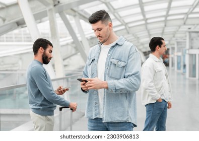 Digital Explorer. Serious Traveler Guy Using Mobile Phone Browsing Internet While Waiting For His Flight Standing In Line To Departure Gate At Airport Indoor. Travel Application And Communication - Shutterstock ID 2303906813