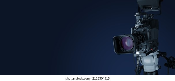 Digital film camera in the dark wall background. Video camera for film production,