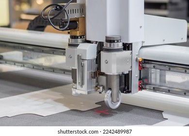 Digital flatbed cutter, plotter cutting white cardboard sheet at printer exhibition, trade show - close up. Technology, industrial, manufacturing, robotic, electronic concept - Shutterstock ID 2242489987