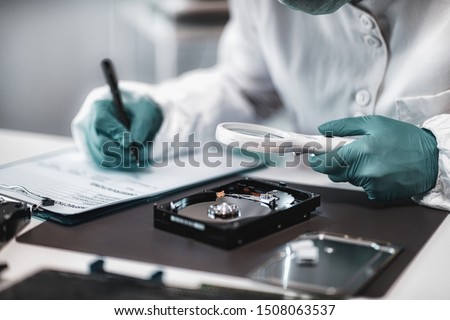 Digital Forensic Science. Police Forensic Analyst Examining Computer Hard Drive.