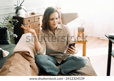 Digital Frustration. Perplexed and irate young woman encounters issues during video call or online ordering in her living room. Technological Challenges and Emotional Distress