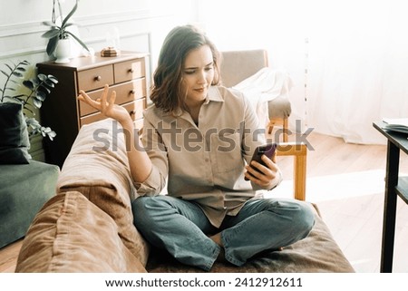 Digital Frustration. Perplexed and irate young woman experiences issues during a video call or online ordering in her living room. Technological Challenges and Emotional Distress