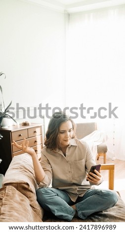 Digital Frustration. Perplexed and irate young woman experiences issues during a video call or online ordering in her living room. Technological Challenges and Emotional Distress
