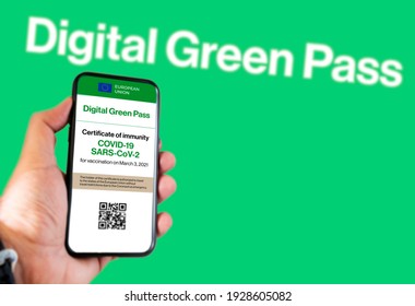 The digital green pass of the EU with the QR code on the screen of a mobile held by a hand with a blurred green background. Immunity from Covid-19. Permit to travel without restrictions in Europe.
