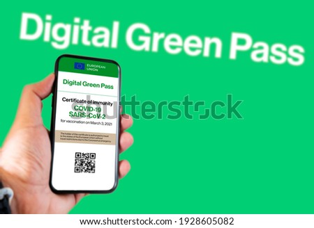 The digital green pass of the EU with the QR code on the screen of a mobile held by a hand with a blurred green background. Immunity from Covid-19. Permit to travel without restrictions in Europe.