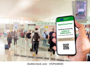 The digital green pass of the european union with the QR code on the screen of a mobile held by a hand with blurred airport in the background. Immunity from Covid-19. Travel without restrictions. - Shutterstock ID 1929104033
