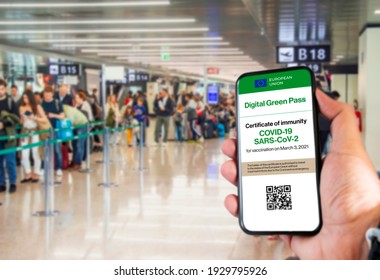 The digital green pass of the european union with the QR code on the screen of a mobile held by a hand with blurred airport in the background. Immunity from Covid-19. Travel without restrictions. - Shutterstock ID 1929795926